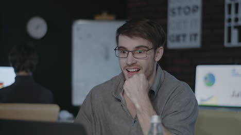 happy business man checking report in front of laptop in dark office.