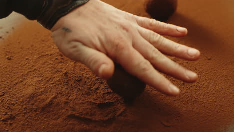 chef rolling truffle ball in cocoa powder in slow motion.