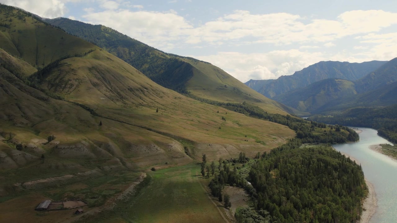 Riprese con drone dell'ampia Valle Ak-Kem con dolci colline verdi, foresta di conifere e un fiume sinuoso sotto un cielo nuvoloso, Repubblica dell'Altai, Russia, paesaggio di viaggio estivo.