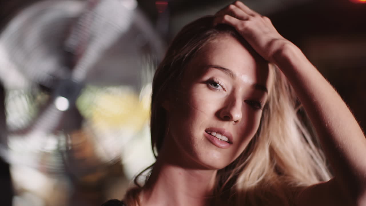 헬스 클럽 2에서 머리를 통해 손을 움직이는 웃는 매력적인 여성 운동 선수의 슬로우 모션