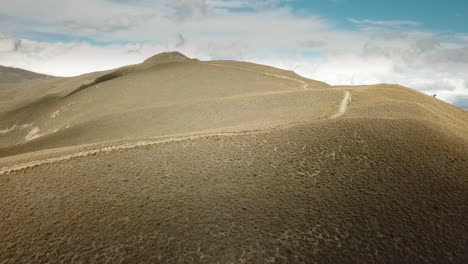 AERIAL-CLIMBING---A-winding-path-up-a-mountain-range,-New-Zealand