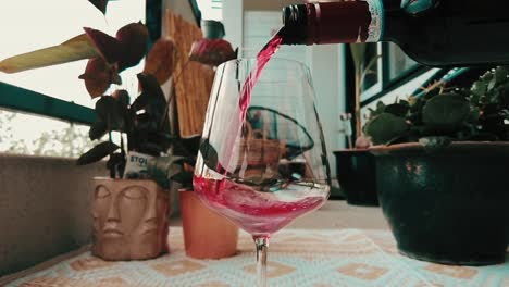 red wine starts being poured in a glass in slow motion in outdoor garden