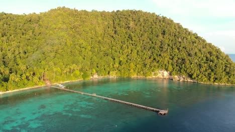 una impresionante vista aérea de la isla de kri en raja ampat, indonesia, captura un largo muelle de madera que se extiende en las aguas turquesas