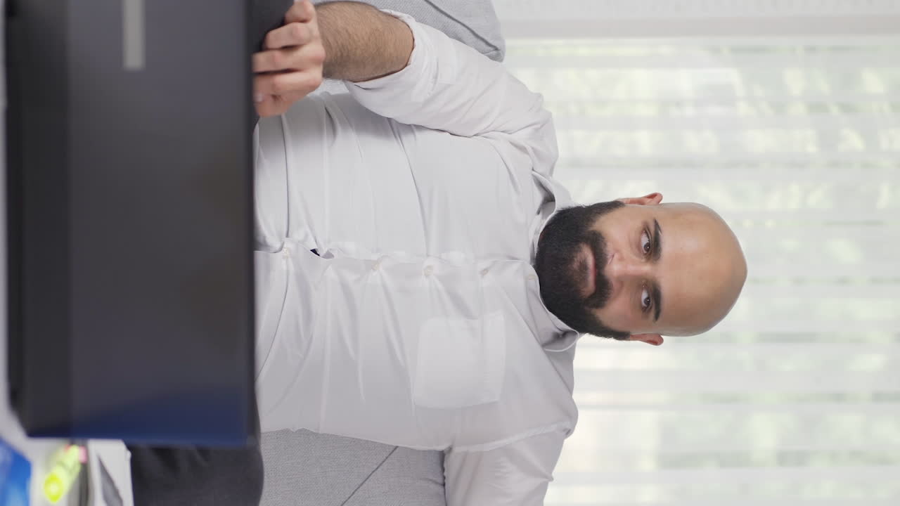 video vertical de un trabajador de oficina en casa mirando nerviosamente a la cámara.