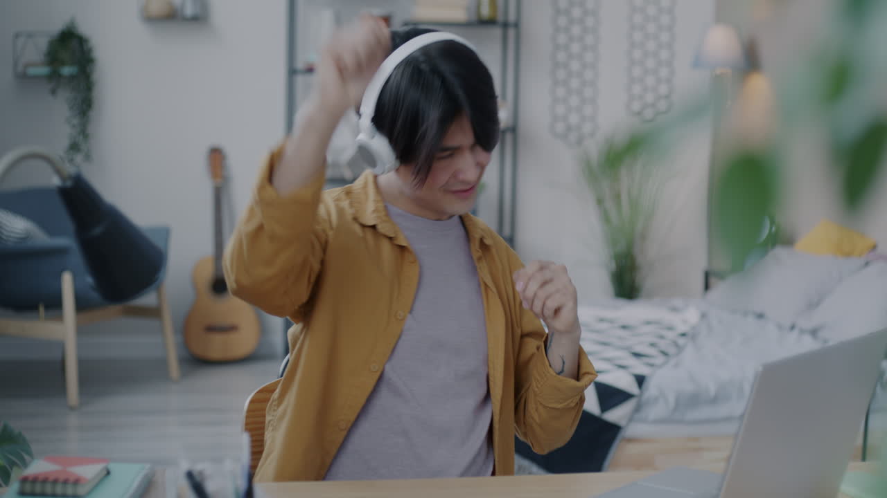 Young Man Dancing to Music While Working on Laptop