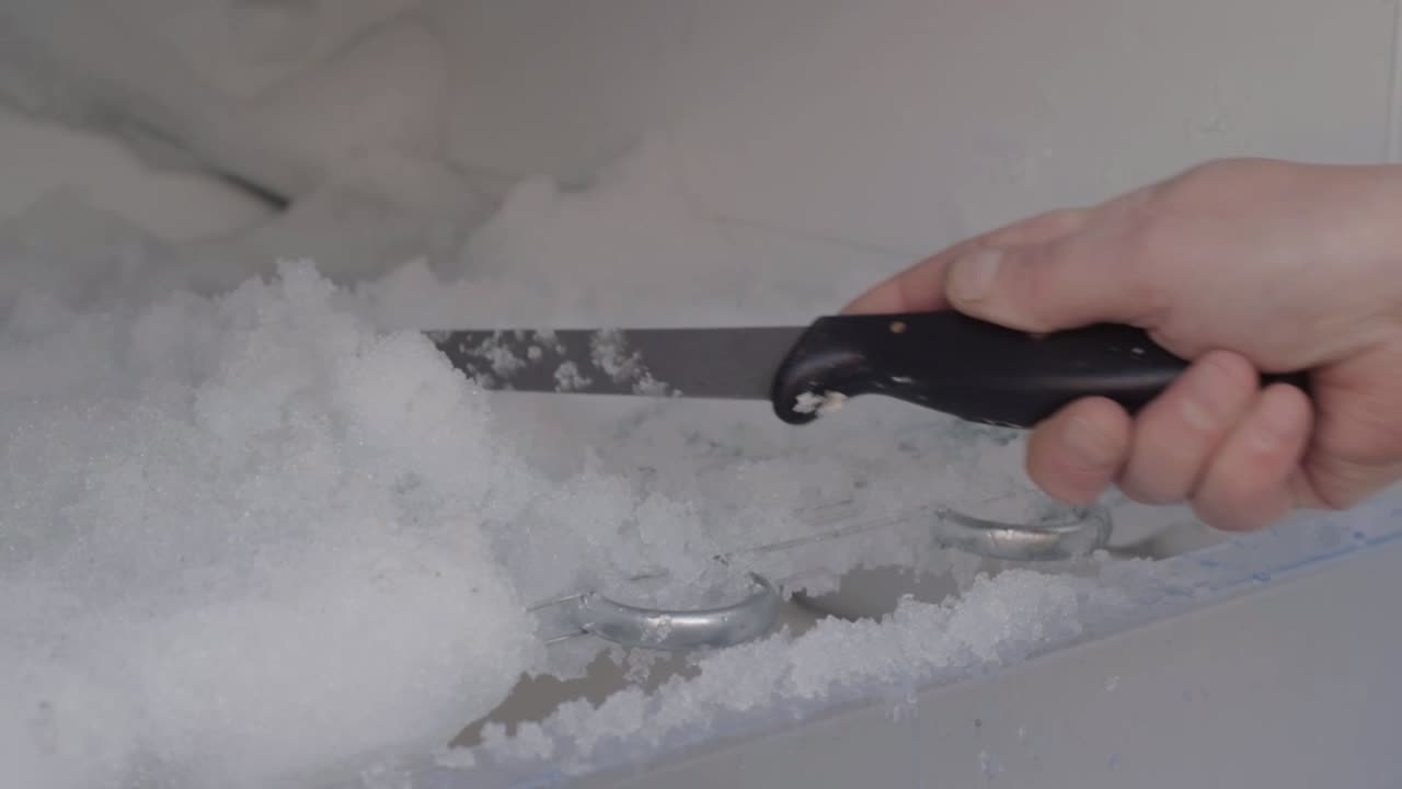 얼음을 치우기 위해 칼을 사용하여 냉장고 해동