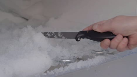 defrosting refrigerator using knife to clear away ice