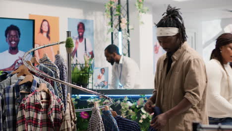 Man-closely-looking-at-shirts-in-mall