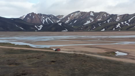 Drohnenansicht-Erstaunliche-Landschaft-Der-Isländischen-Landschaft-Mit-Hohem-Schneeberggipfel.-Vogelperspektive-Des-4x4-Offroad-Expeditionsfahrzeugs,-Das-Auf-Unbefestigten-Straßen-Im-Isländischen-Hochland-Fährt