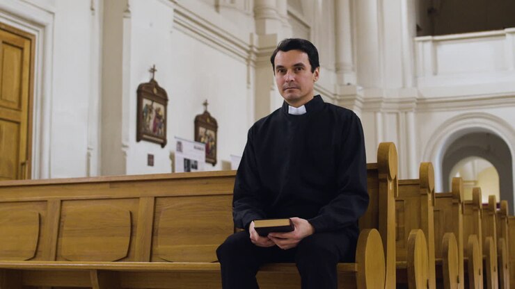 Priest sitting on a bench indoors