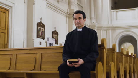 priest sitting on a bench indoors