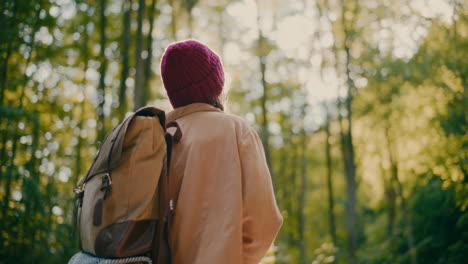 young woman with backpack hiking in forest