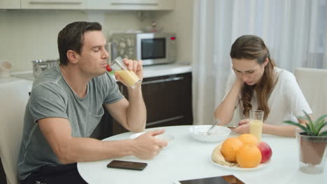 una pareja seria comiendo un desayuno saludable en la cocina de su casa juntos.