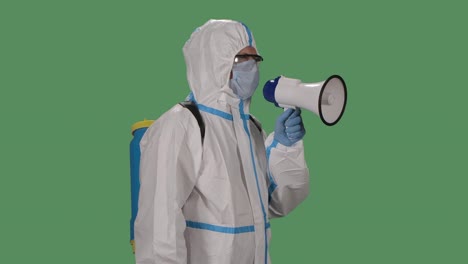 portrait of a man in a protective suit, glasses, gloves and a medical mask speaks into a megaphone warning people about the dangerand asks to go away. green screen, chroma key. slow motion. close up