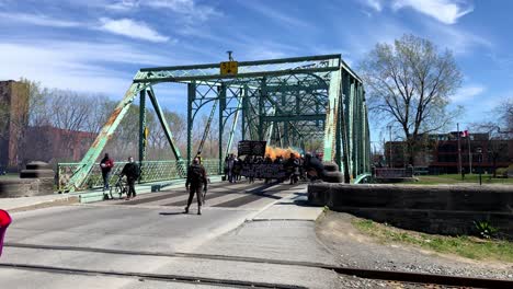 protestors demonstrating with smoke flares and carrying placards walking across a steel bridge while pedestrians look on.
