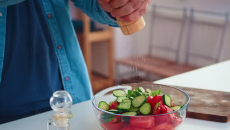 pouring salt over healthy salad