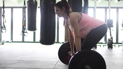 footage of a pregnant female model doing squats in a gym trying to keep fit in her fourth trimester