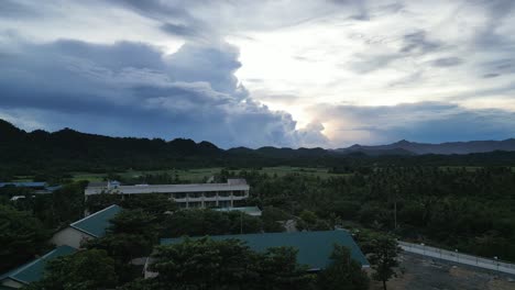 Ascenso-Aéreo-Del-Pueblo-Con-La-Construcción-De-Nubes-De-Tormenta-Cumulonimbus-Al-Atardecer,-Catanduanes,-Filipinas