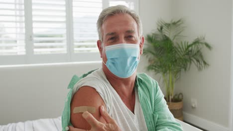 caucasian senior man wearing face mask and plaster after vaccination