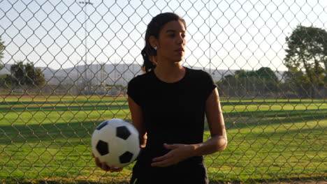 a strong and confident female athlete soccer player holding a football during a competitive womens sports game in a field slow motion