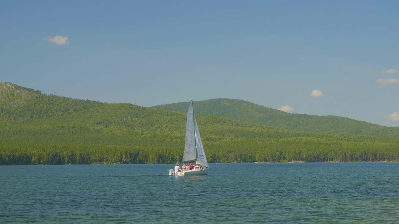 парусная лодка на спокойном озере с горами на заднем плане
