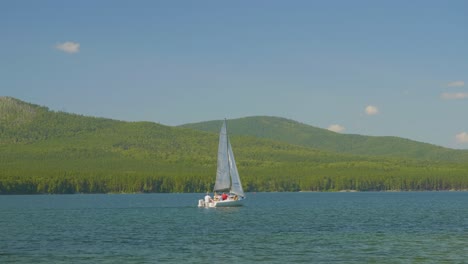 velero en un lago tranquilo con montañas en el fondo