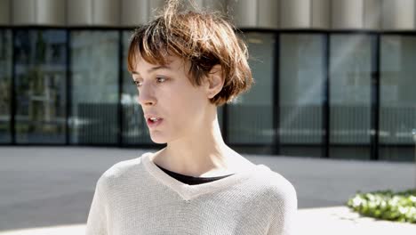 front view of serious young woman talking to someone on street