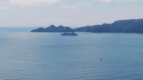 aerial shot of mediterranean sea with a cruise ship, calm water, and distant island in italy