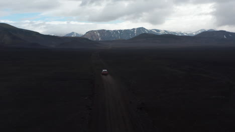 Birds-eye-view-of-car-driving-offroad-exploring-Lakagigar-black-volcanic-desert.-High-angle-view-of-Skaftafell-national-park-with-snowy-mountains-peak.-Commercial-insurance.-Amazing-in-nature