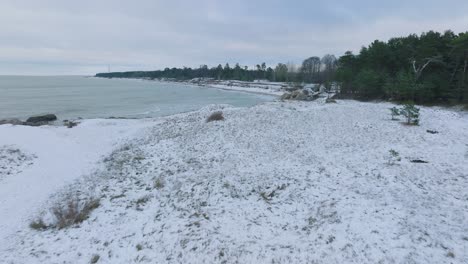 aerial establishing view of abandoned seaside fortification buildings at karosta northern forts on the beach of baltic sea , overcast winter day, wide drone shot moving forward low