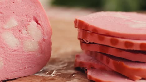 ham italian mordatella, man slices of traditional italian antipasti mortadella sausage on a wooden cutting board, close up macro of chicken or turkey jamon, fat breakfast dish.