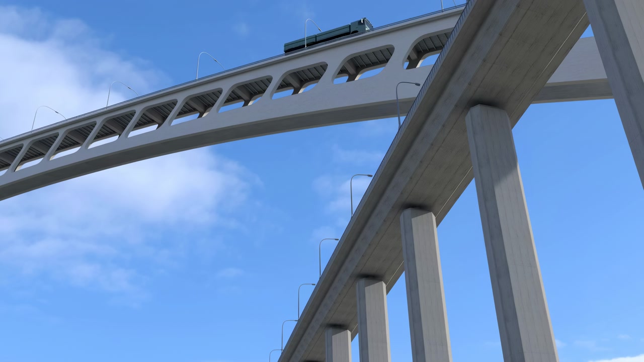 別の高架道路の上を横切る大きなコンクリート橋のローアングル。高い支持柱と曲線を描く橋桁があり、空には薄い雲が浮かんでいる。