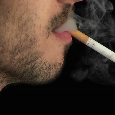 Un-Hombre-Con-Una-Barba-Desaliñada-Enciende-Un-Cigarrillo-De-Perfil-Y-Lo-Fuma