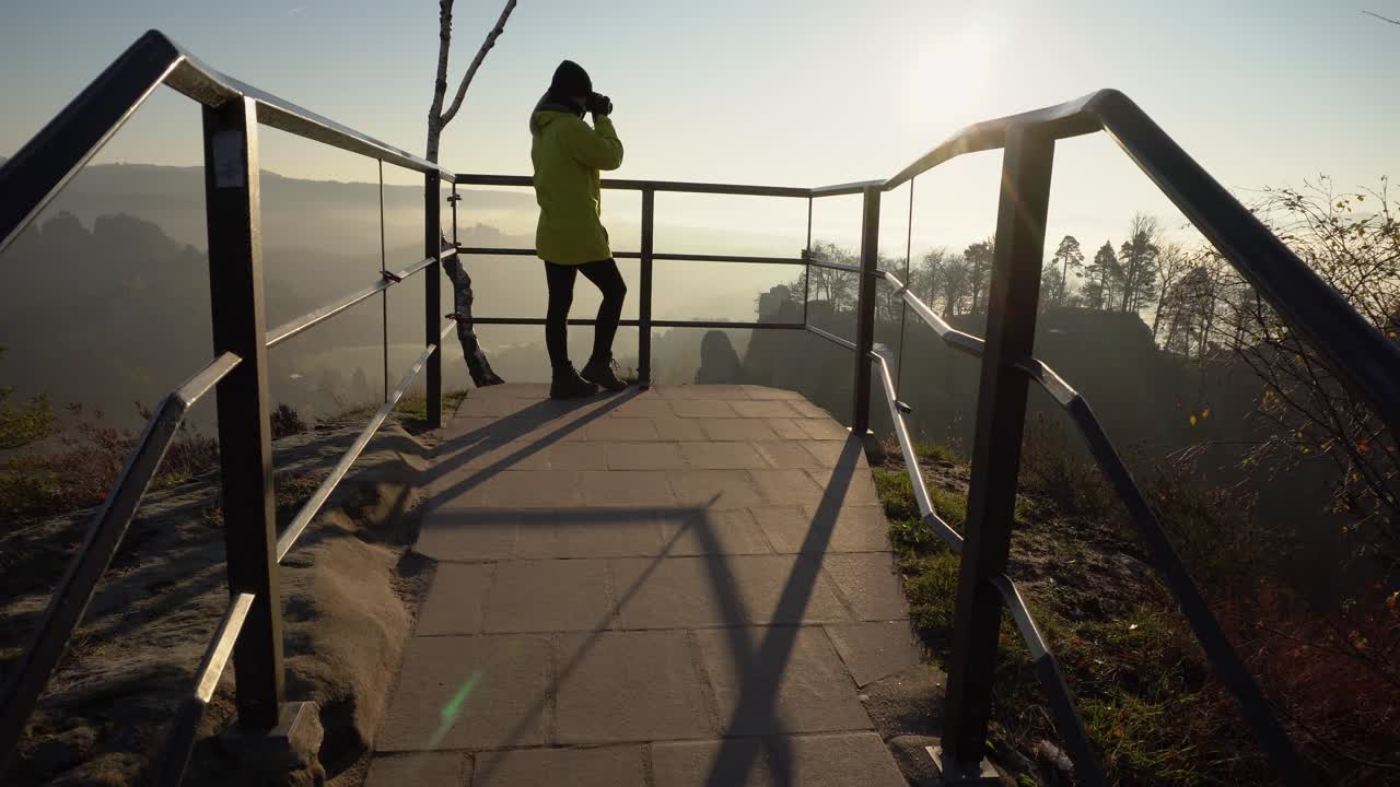 chica con chaqueta amarilla toma una foto del hermoso paisaje en un día frío, toma de cardán