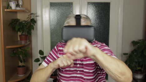 grandmother in virtual headset glasses watching video in vr helmet training box, shows fist fight