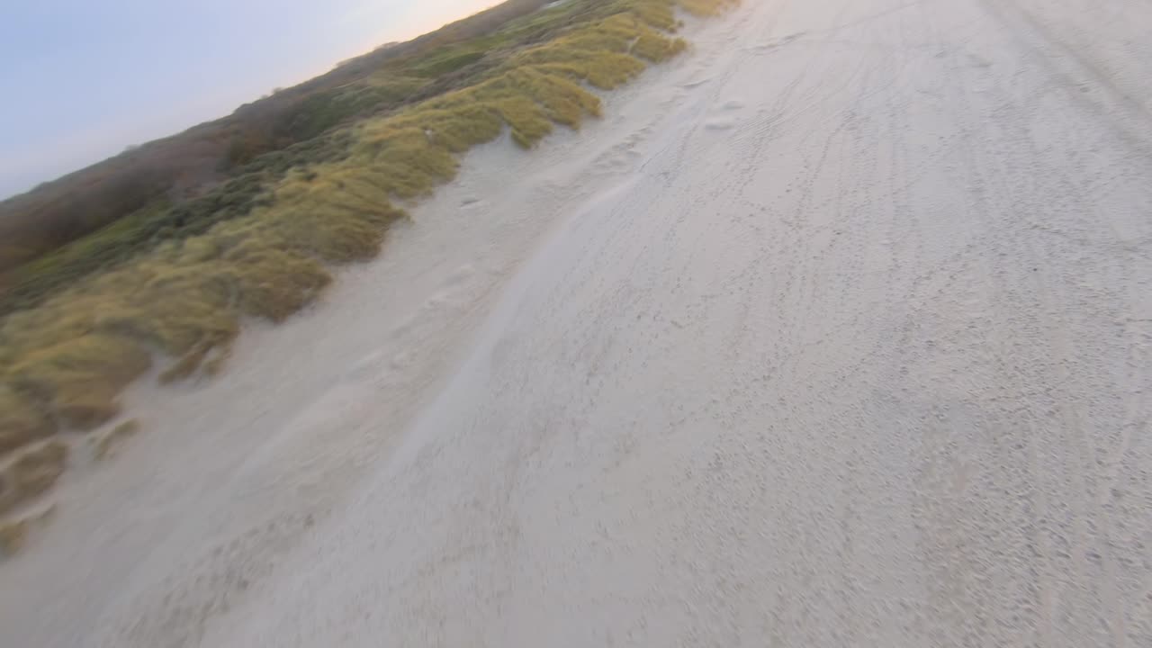 Drone flying over the dunes of Oostkapelle during a sunset