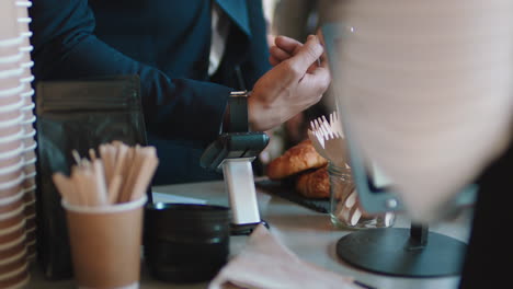 close up customer making contactless payment using smart watch mobile money transfer spending money in cafe with digital transaction service technology