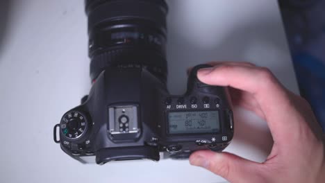 photographer's hand spinning the main command dial of a dslr camera on the table - overhead shot