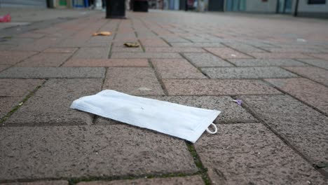 Basura-De-La-Máscara-Facial-Del-Virus-De-La-Corona-En-El-Suelo-En-Una-Tranquila-Calle-De-Ladrillos-De-La-Ciudad