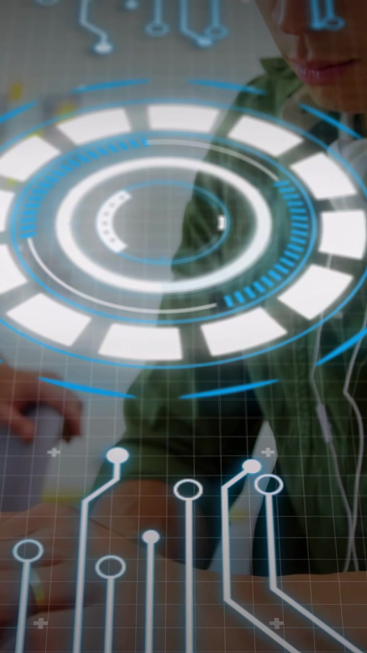 Vertical video: Man typing on laptop making AR HUD pulse and rotate, partner pointing, for tech