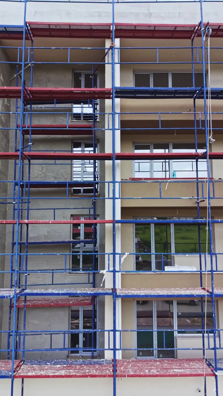 Byggeri i gang af en etageejendom med stillads på ydermurene til arbejdere og sikkerhed.