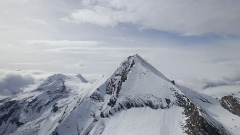 cinematic aerial panorama shot of snowy mountain formation with peaks during sunny day at sky