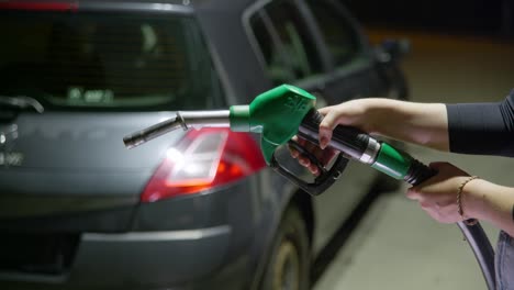 person holding a green unleaded fuel handle which is out of service, because there is petrol shortage