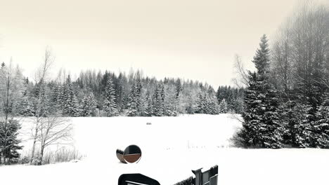 Aerial-small-cabin-in-winter-landscape-in-white-snow-covered-spruce-forest,-Riga-Latvia