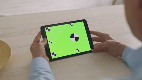 online application for seniors. blank digital tablet with green chroma key screen in male senior wrinkled hands