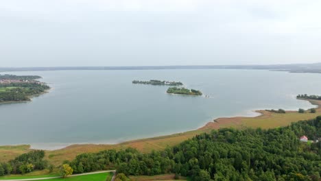 chiemsee, bavaria, germany - a view of freshwater lake surrounded by lush greenery - aerial pullback