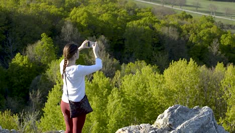 girl in the white top and dark red leggings taking pictures of the nature