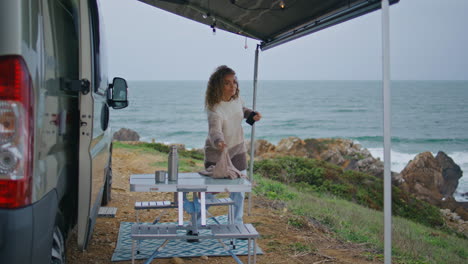 woman walking out motorhome to beautiful ocean coast. curly lady wearing scarf