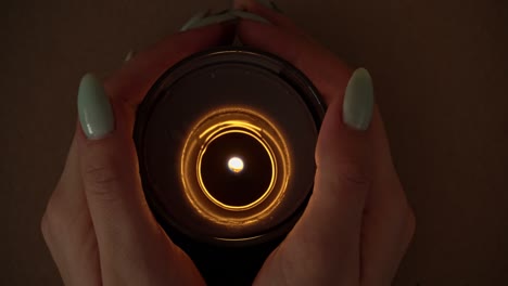la vela arde atmosféricamente en las manos de una chica con una hermosa manicura.