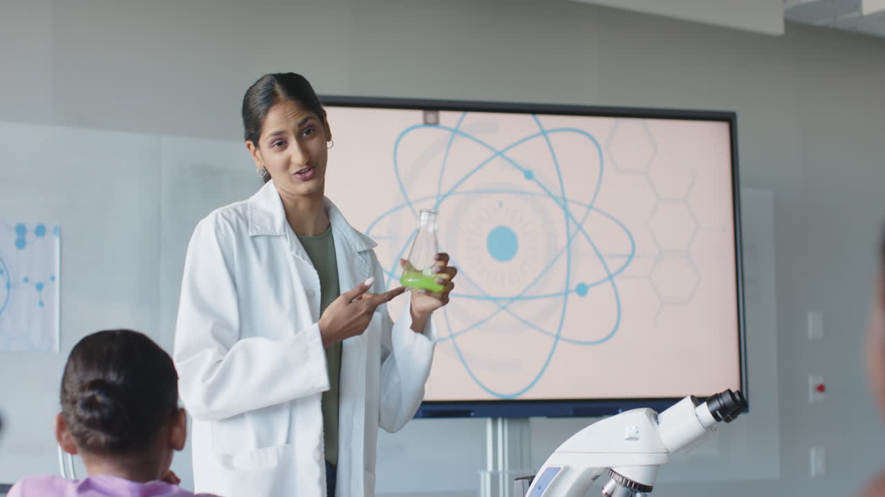 Teaching science, woman in lab coat holding flask and smiling in classroom
